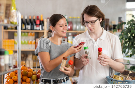 In shop youth girl and guy scan QR code and take reading spices and herbs package using phone camera 142766729
