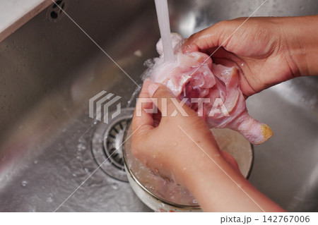 Washing chicken in a kitchen sink before preparing a meal 142767006