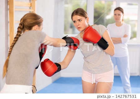 Teenage girl in boxing gloves practicing punches in sparring at self defense training 142767531