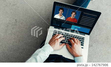 Person using a laptop to create a deep fake video at home in the evening 142767906