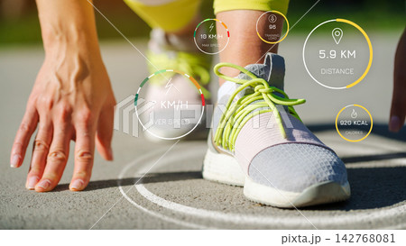 Person getting ready to run while checking running metrics on a sports app on a track in a bright outdoor setting Person getting ready to run while checking running metrics on a sports app on a track in a bright outdoor setting 142768081