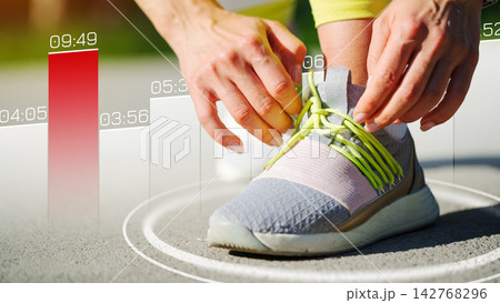 Athlete tying shoelaces before running on a track during morning hours 142768296