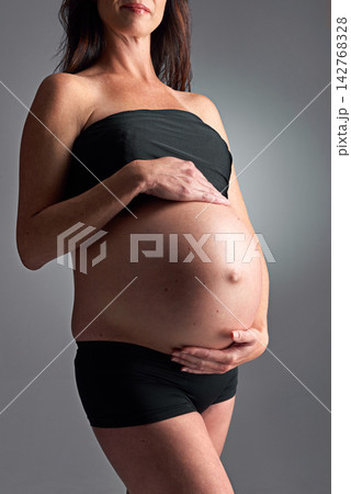 Studio, pregnant and person with care for stomach, growth and health of baby, body and glow with cosmetics. Grey background, mom and child in belly or abdomen, shine and skincare for woman and skin Studio, pregnant and person with care for stomach, growth and health of baby, body and glow with cosmetics. Grey background, mom and child in belly or abdomen, shine and skincare for woman and skin 142768328