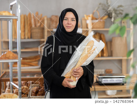 Woman in black hijab searching for fresh baked goods in bakery 142768364