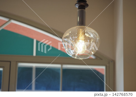 Light bulb hanging from the ceiling in a cafe with colorful decor Light bulb hanging from the ceiling in a cafe with colorful decor 142768570