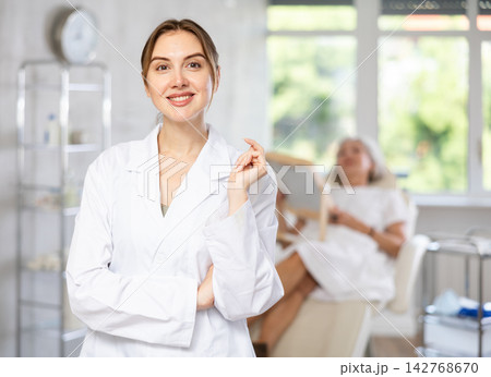 Female doctor cosmetologist stand with woman looking mirror behind in the doctors office. 142768670