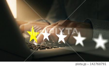Person giving feedback rating on a laptop in a dimly lit room during evening hours Person giving feedback rating on a laptop in a dimly lit room during evening hours 142768791