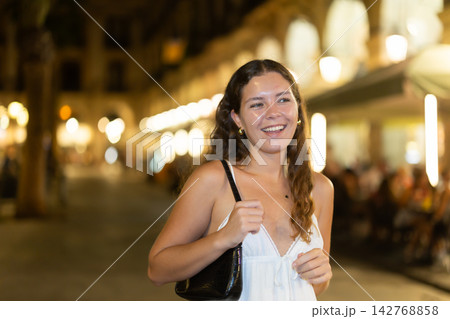 In night, young smiling girl walks along city street Placa Real 142768858