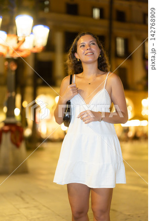 young woman walks along an evening street in Barcelona 142768909