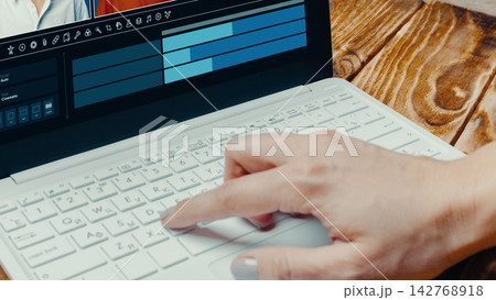 Person uses laptop to create deep fake video in a bright room with wood table and electronic tools Person uses laptop to create deep fake video in a bright room with wood table and electronic tools 142768918