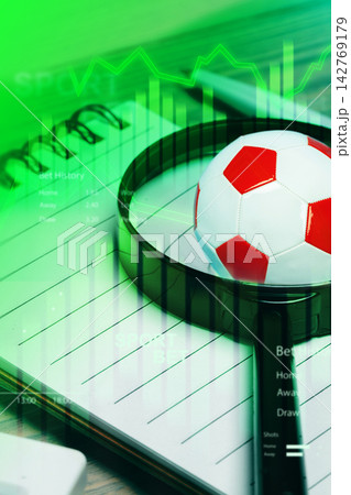 Sport betting setup with soccer ball, data charts, and notebook on a desk for analysis and planning Sport betting setup with soccer ball, data charts, and notebook on a desk for analysis and planning 142769179