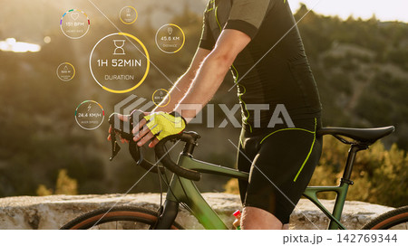 Cyclist checking performance data after a long ride in the mountains during sunset Cyclist checking performance data after a long ride in the mountains during sunset 142769344