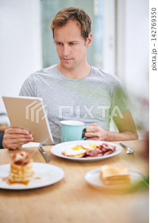 Happy, man and breakfast with tablet at table for morning routine with rest, relax and entertainment on holiday at home. Online, male person and tech for watching tv or streaming movies on vacation 142769350