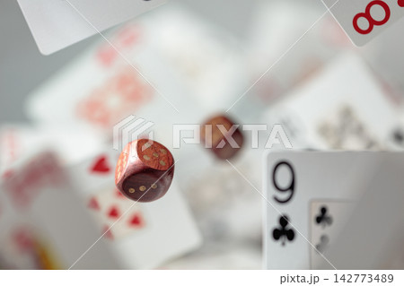 Wooden die in motion surrounded by playing cards. Wooden die in motion surrounded by playing cards. 142773489