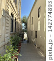 Passage in the old town between houses. An alleyway or a narrow passage between buildings, sunny day, no people. 142774893