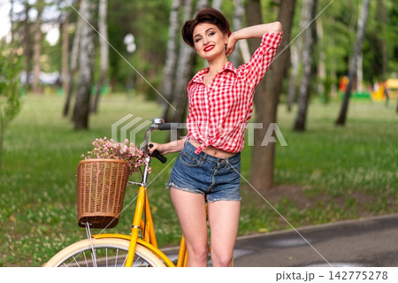 A retro girl riding a yellow bicycle in park 142775278