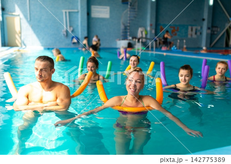 People training with pool noodles in water 142775389