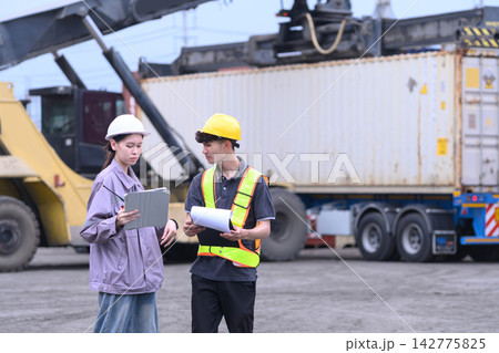 Industrial workers checking shipment documents and digital logistics data at shipping yard Industrial workers checking shipment documents and digital logistics data at shipping yard 142775825