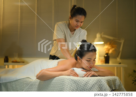 Woman enjoying back massage at spa with therapist in warm calm wellness room 142775858