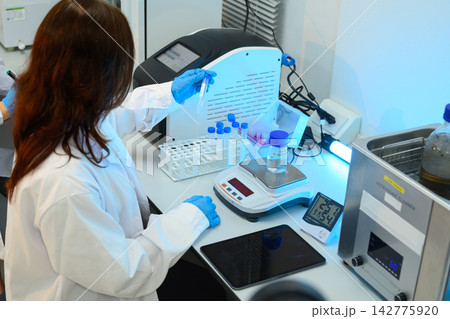 Female Scientist Working in Modern Laboratory with Test Tubes, Scale, and UV Equipment Female Scientist Working in Modern Laboratory with Test Tubes, Scale, and UV Equipment 142775920