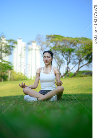 Beautiful woman practicing yoga meditation with city backdrop, calm urban mindfulness Beautiful woman practicing yoga meditation with city backdrop, calm urban mindfulness 142775979