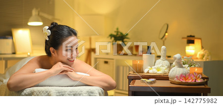 Young woman enjoying relaxing massage therapy at spa, lying on massage table 142775982