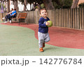 Toddler boy playing with ball in park 142776784
