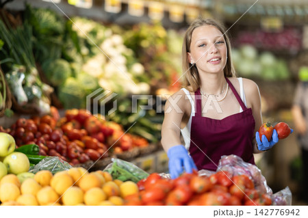 female seller lays out tomatoes on the counter female seller lays out tomatoes on the counter 142776942
