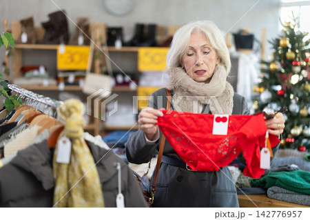 Mature female shopper selects panties in fashionable clothing boutique Mature female shopper selects panties in fashionable clothing boutique 142776957