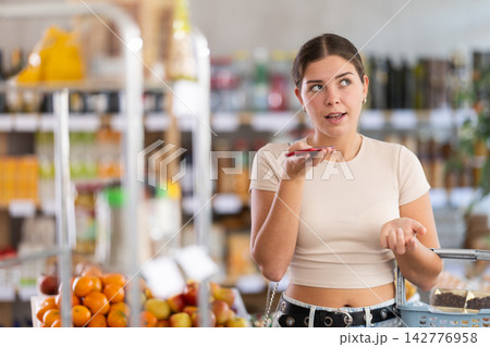 Young woman choosing groceries while records voice message Young woman choosing groceries while records voice message 142776958