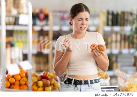 Young woman with rotten apples in grocery store Young woman with rotten apples in grocery store 142776979