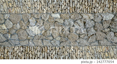 Rustic limestone rock wall built with stacked natural stones and varied rough masonry courses Rustic limestone rock wall built with stacked natural stones and varied rough masonry courses 142777054