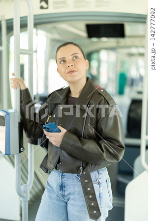 Young woman standing in tram with smartphone Young woman standing in tram with smartphone 142777092