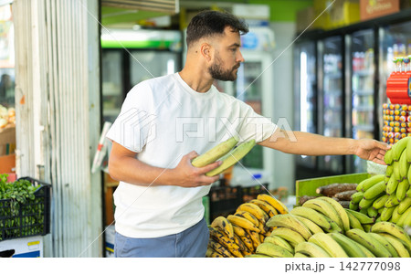 Man customer in supermarket search, choose cooking banana goods Man customer in supermarket search, choose cooking banana goods 142777098