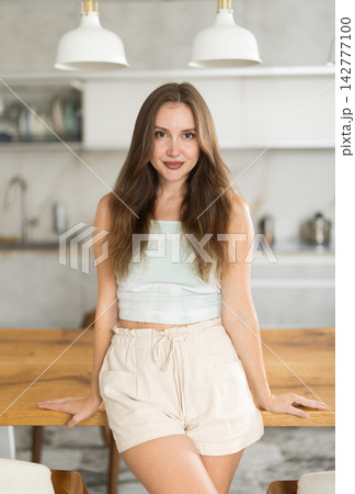 Adult woman in shorts posing in kitchen Adult woman in shorts posing in kitchen 142777100