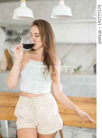 Woman drinking wine in bright kitchen Woman drinking wine in bright kitchen 142777179