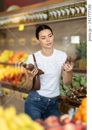 Girl shopping in grocery supermarket - choosing yucca root 142777186