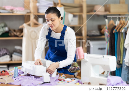 Female repairman fixing sewing machine 142777292