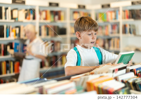 Teenage boy choosing book in bookstore Teenage boy choosing book in bookstore 142777304