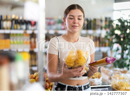 Young woman is holding packages of pasta and spaghetti in hands, choosing food for garnish side dish 142777307