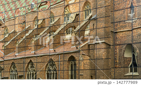 Abstract reflection of a historic Gothic brick church on a modern glass facade. 142777989