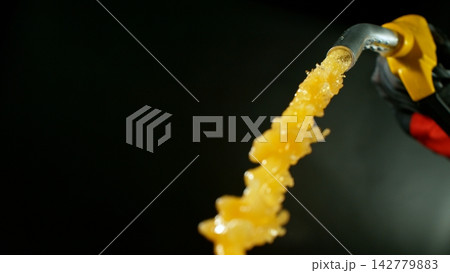 Close-up of Gasoline Spurting from the Gas Pump Nozzle , Dark Grey Background Close-up of Gasoline Spurting from the Gas Pump Nozzle , Dark Grey Background 142779883