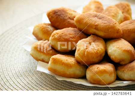 Stack of golden fried pirozhki pies served on plate for bakery design 142783641