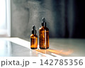 Skincare bottles presenting essence and atomized mist droplets 142785356