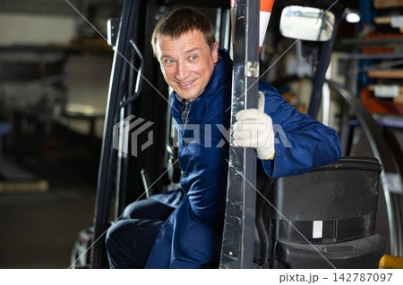 Adult man posing while sitting in forklift 142787097