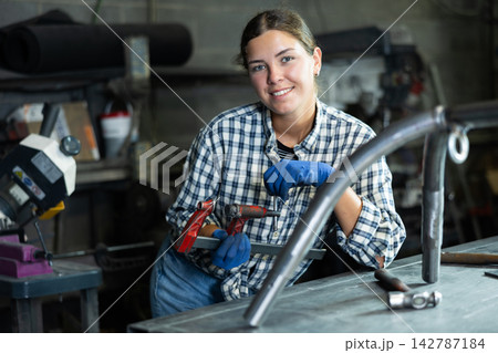 Young woman posing with vice in workshop Young woman posing with vice in workshop 142787184