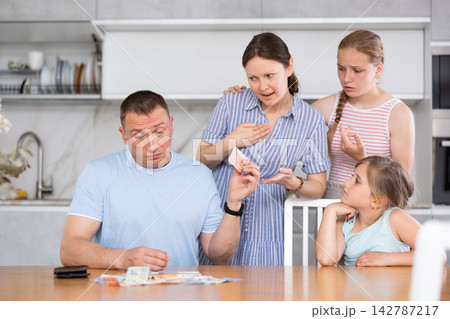 Dissatisfied husband and father give out pocket money to wife and children in kitchen 142787217