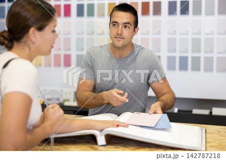 Seller of hardware store advises woman of buyer what ceramic tiles to buy Seller of hardware store advises woman of buyer what ceramic tiles to buy 142787218