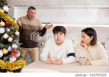 Domestic quarrel during Christmas celebration - father scolds and shouts at young gyuy and girl 142787220