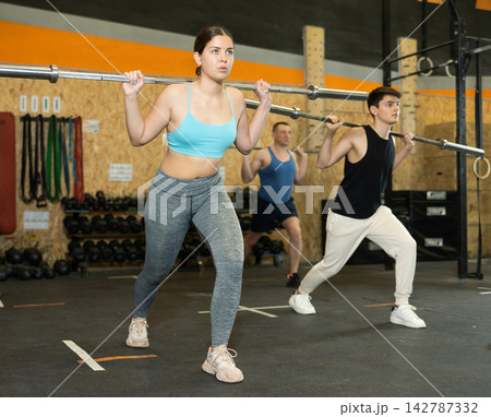 Sporty young girl doing exercises with barbell in gym Sporty young girl doing exercises with barbell in gym 142787332
